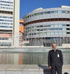Dr. Khurram Saadiq standing in front of the central fountain outside of the UN HQ in Vienna