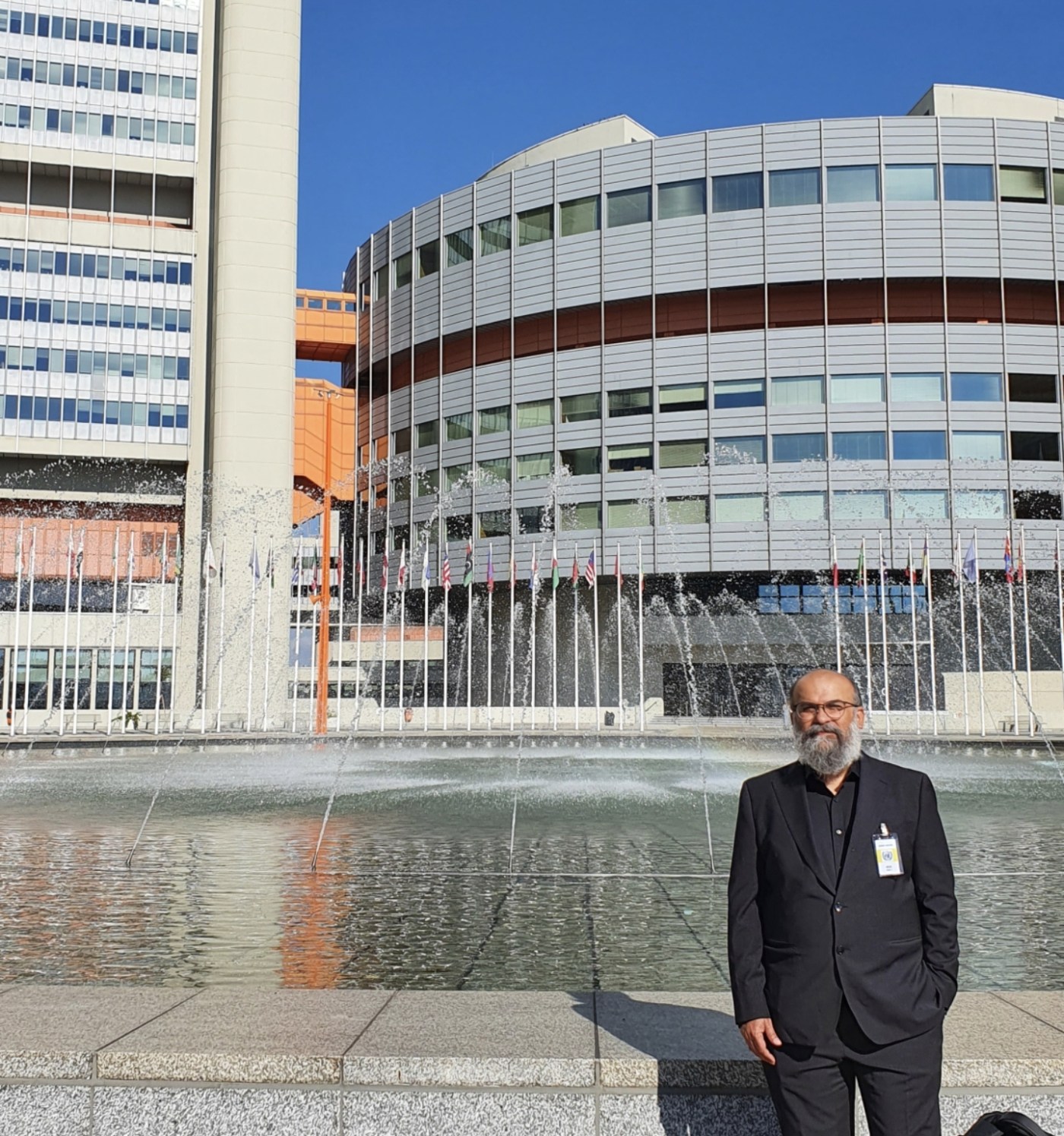 Dr. Khurram Saadiq standing in front of the central fountain outside of the UN HQ in Vienna